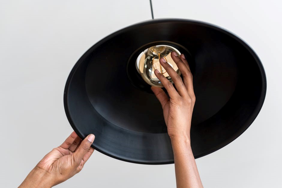 woman changing light bulb on black barn light