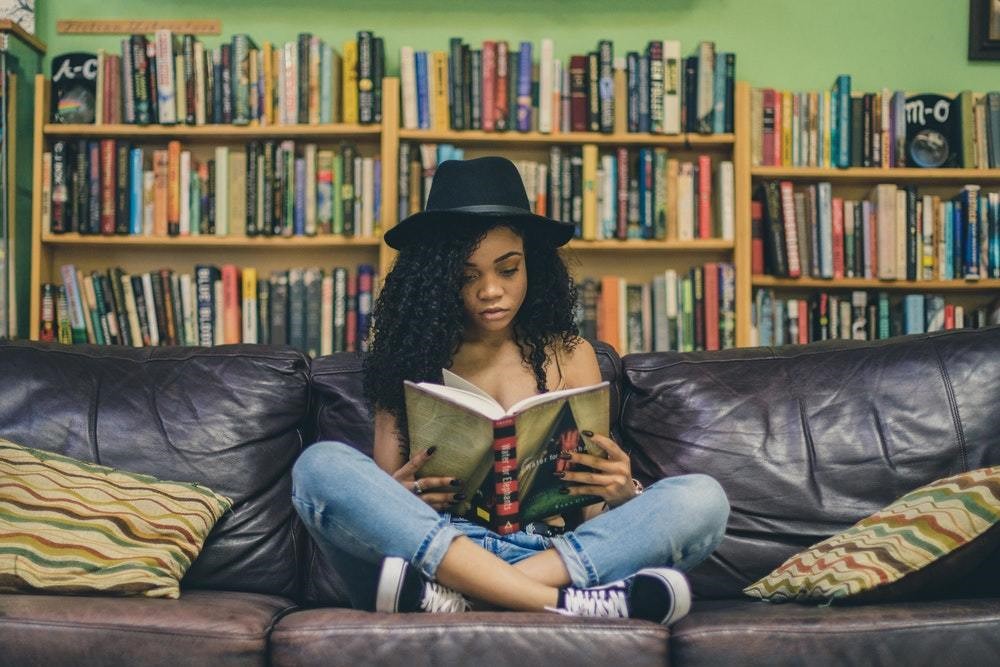 black woman with black hat reading a book