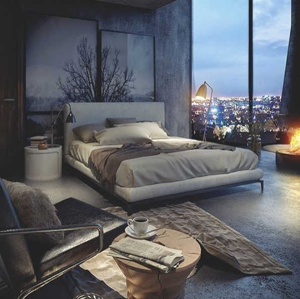 brown bed in large bedroom loft overlooking the city with forest paintings on wall