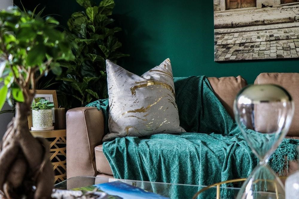 grey pillow with gold streaks on a grey couch with teal blanket