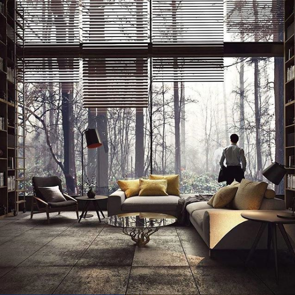 guy standing in large home in front of large window looking out to a dreary forest