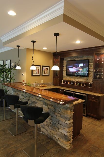 home bar made out of stone with black pendant lights