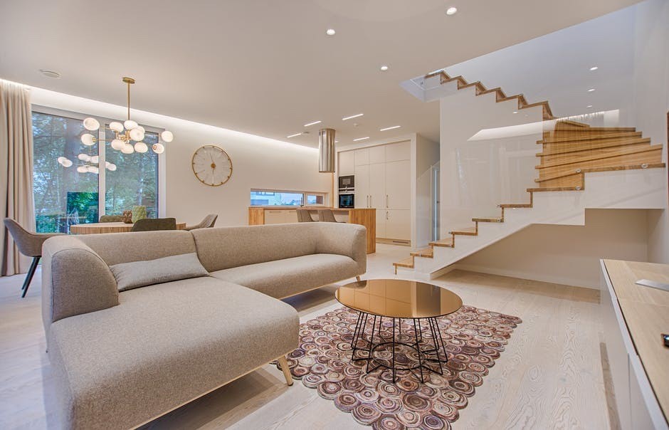 luxury living room with grey couches and wooden stairway