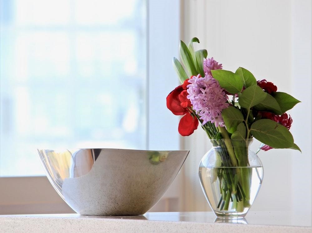 metallic bowl on countertop next to pretty flower vase with roses