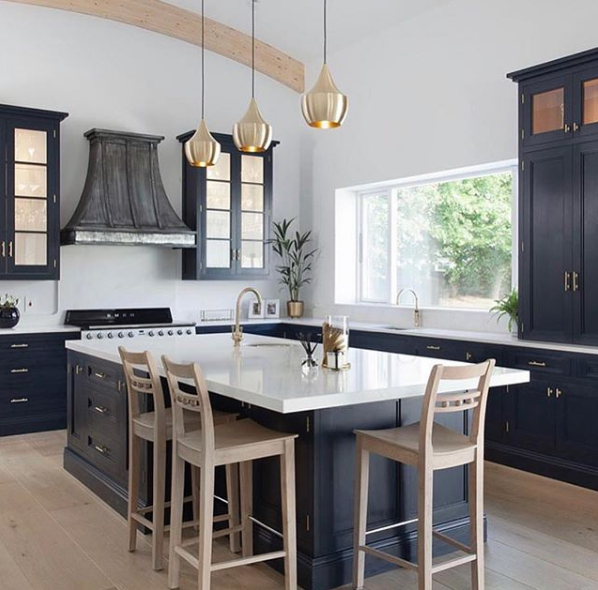 white kitchen island countertop on black island with gold pendants